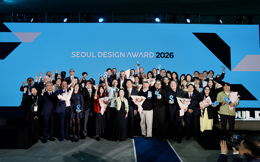 Vincitori del Seoul Design Award sul palco, con vari trofei blu sollevati davanti a uno schermo blu